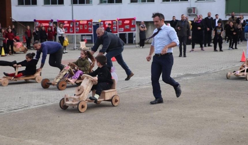 İlçedeki özel bir okulda gerçekleştirilen etkinliğe babalarıyla katılan 12 çocuk, düz parkurda ailelerinin hazırladığı tahta arabaları sürdü.