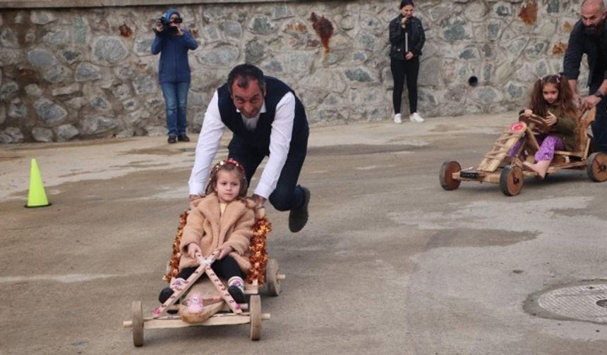 Ana sınıfı öğrencisi çocukların yarışına, babaları tahta arabaları iterek destek verdi.